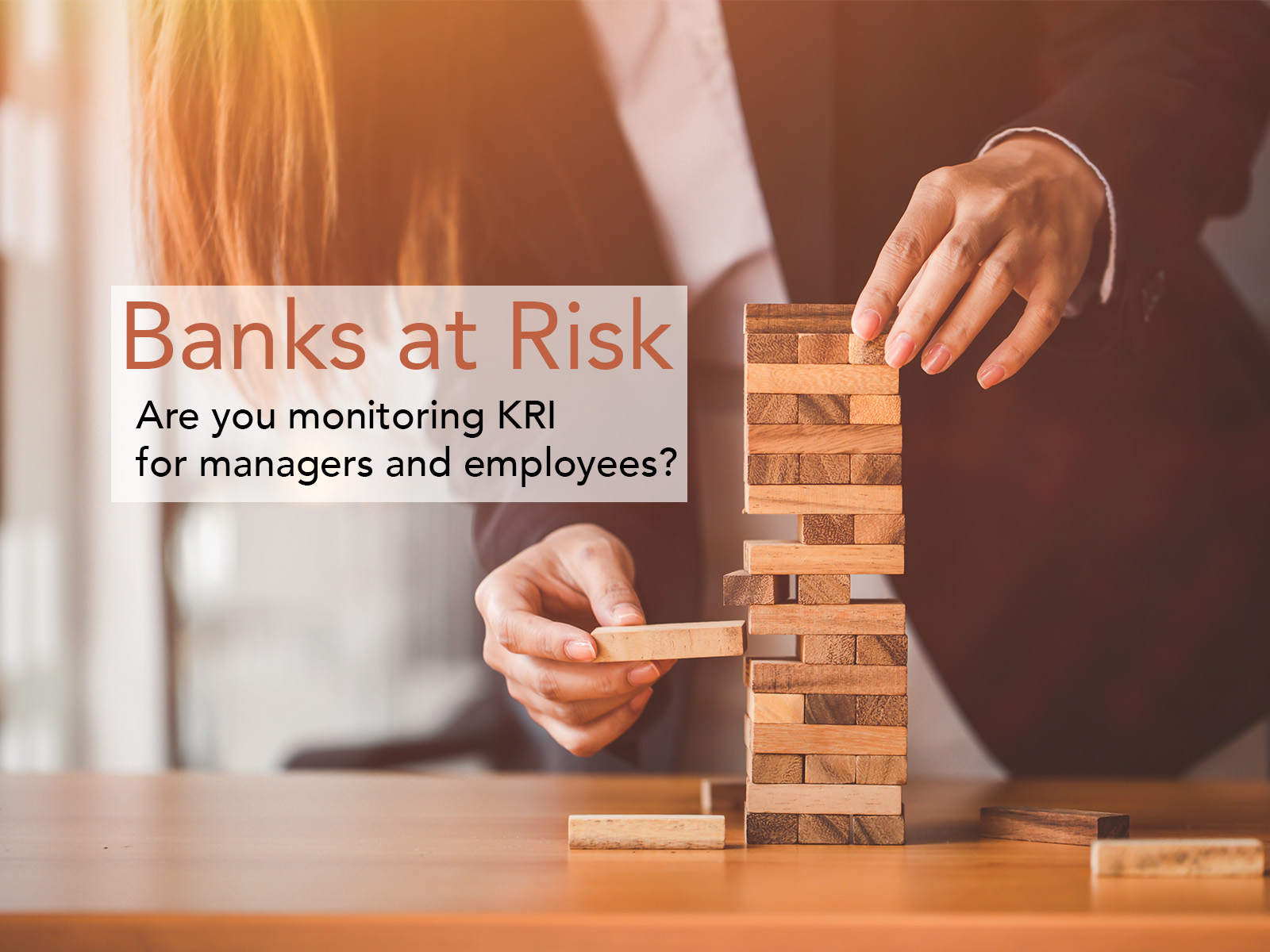 Photo illustration of business person destabilizing a small tower of wooden blocks. Text on image: Banks at Risk: Are you monitoring KRI for managers and employees? The point of image/story: In Risk Management and AML Compliance, financial institutions must use RegTech solutions to automate monitoring of Key Risk Indicators pointing toward malfeasance by employees and managers.